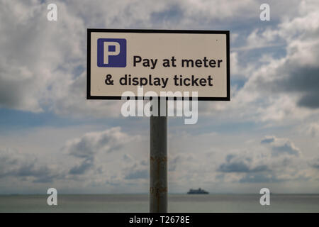 Segno: pagare al metro & display ticket, visto in St Margaret a Cliffe, Kent, Regno Unito - con le nuvole e una traversata in traghetto il canale britannico nel Foto Stock