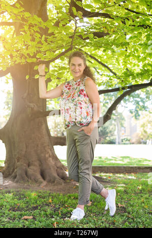 Ritratto di sorridere donna matura in un parco indossando top con disegno floreale Foto Stock