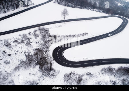 Austria, Wienerwald, auto guida su strada di montagna nel paesaggio innevato, vista aerea Foto Stock