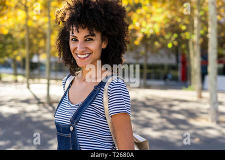 Ritratto di una donna sorridente, stando in piedi in un parco Foto Stock