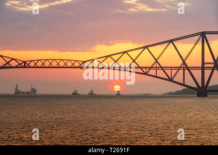 Regno Unito, Scozia, Firth of Forth, Ponte di Forth Rail con barche rimorchiatore sotto il Segugio e punto di caricamento di olio Terminale marino al tramonto Foto Stock