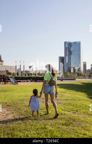 Madre e figlia camminando mano nella mano in un parco Foto Stock