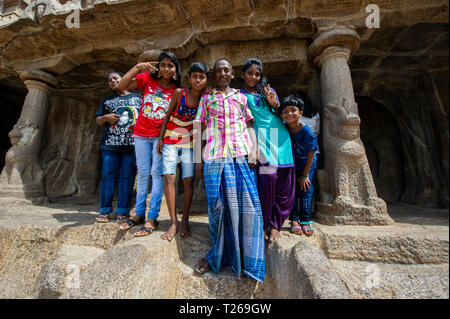 Una grande famiglia pongono per la telecamera in Monumenti a Mahabalipuram vicino a Chennai, India. I bambini indossare abiti occidentali. Foto Stock