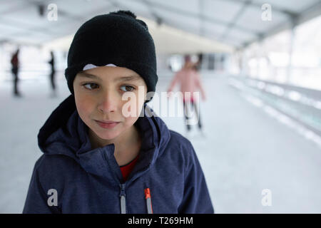 Ritratto di un ragazzo, indossando wooly hat, divertirsi sul ghiaccio la pista di pattinaggio su ghiaccio Foto Stock