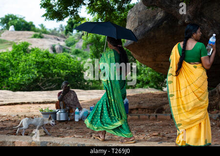 Eleganza presso i monumenti di Mahabalipuram vicino a Chennai, India come donne passeggiata in campagna, proteggersi dal sole con un ombrellone Foto Stock