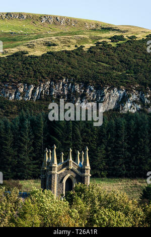 Scenario di frontiera in Cheviot colline dove si unisce la Scozia in Inghilterra. Kirk Yetholm (fine del The Pennine Way) chiesa con scogliere di cava al di là. Foto Stock