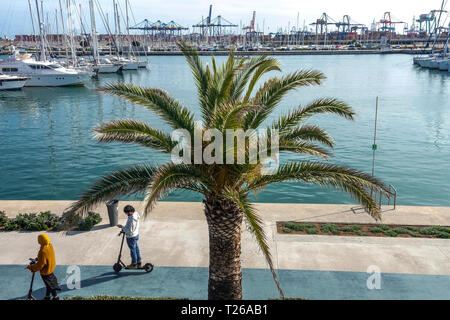 I turisti che si recano su scooter elettrici e che guardano Yacht di lusso e barche a Valencia Marina Real Spain Port Foto Stock