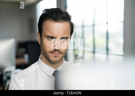 Imprenditore in ufficio a lavorare sul computer nella parte anteriore della finestra Foto Stock