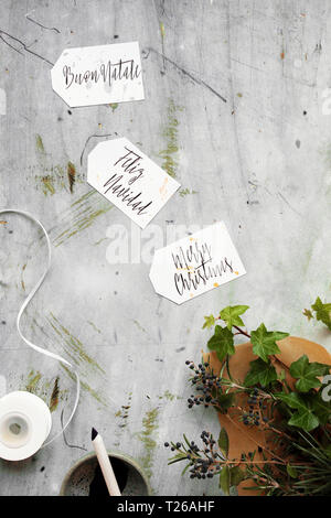 Buon Natale scritto in 3 lingue diverse (inglese, italiano, spagnolo) sul calligraphy dono tags Foto Stock