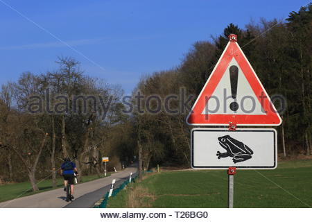 Un triangolare segno rosso driver avverte del pericolo delle rane attraversando la strada in primavera Foto Stock