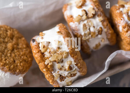 Panini di gelato con i dadi e i cookies integrali. In casa la vaniglia e noci panini di gelato vicino. Foto Stock
