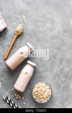 Latte di avena alternativa su sfondo grigio, copia spazio, vista dall'alto. Vegano sano sostituto dairy drink gratuito - bottiglia di latte di avena. Foto Stock