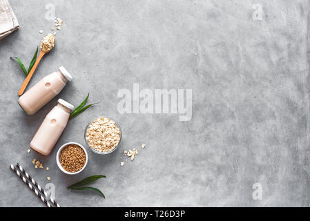 Latte di avena alternativa su sfondo grigio, copia spazio, vista dall'alto. Vegano sano sostituto dairy drink gratuito - bottiglia di latte di avena. Foto Stock