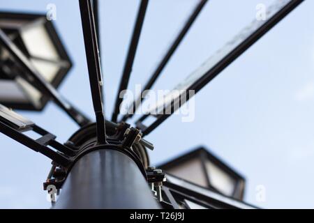 Il lampione è fatta di metallo contro un cielo blu con cartelli di indicazione delle città. Durante il giorno le luci sono spente. Foto Stock