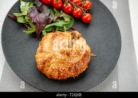 Coscia di pollo in pasta cotta al forno con patate, pomodori, cipolle e spezie con un contorno di pomodori e insalata verde. Foto Stock