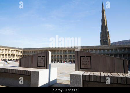 Sedile unico / posti con logo all'interno del pezzo Hall con piazza Chiesa Cappella guglia in background dietro. Sunny / sun & blue sky. Halifax, West Yorkshire, Regno Unito. (106) Foto Stock