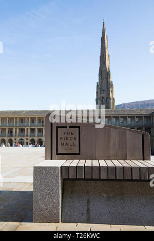 Sedile unico / posti con logo all'interno del pezzo Hall con piazza Chiesa Cappella guglia in background dietro. Sunny / sun & blue sky. Halifax, West Yorkshire, Regno Unito. (106) Foto Stock