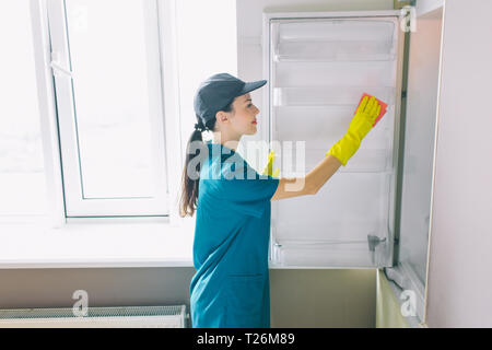 Ragazza con buon umore lavorare in cucina a finestra. Lei bagna all interno di essa. La donna ama il suo lavoro. Sorride Foto Stock