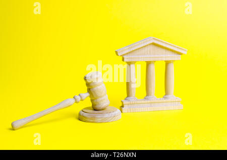 Giudice in legno martello e il palazzo del governo su uno sfondo giallo. Corte. Concetto di stato del sistema giudiziario. Divieti e criminalizzazione, rep Foto Stock