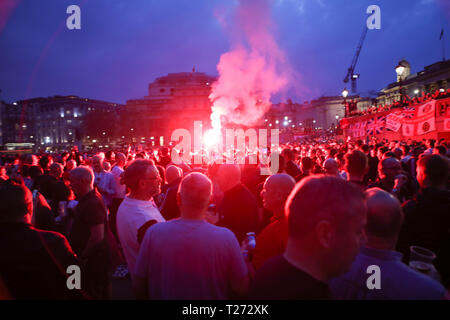 Londra, Regno Unito. 30 marzo 2019. Una grande folla di fan del Sunderland si raduna in una Trafalgar Square di notte, illuminata da una luce rossa che emette fumo e luce intensa. I tifosi del Sunderland in trasferta la sera prima della finale dell'EFL Trophy contro il Portsmouth a Wembley prendono il controllo di Trafalgar Square. Penelope Barritt/Alamy Live News Foto Stock