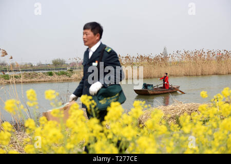 (190331) -- Pechino, 31 marzo 2019 (Xinhua) -- codolo Zhenya offre pacchetti su Riva e sua moglie Yan Ling (R) palette in lago Xintan nel villaggio di Laozishan città nel distretto Hongze dell Huai'an City, est cinese della provincia di Jiangsu, 30 marzo 2019. Il 55-anno-vecchio Zhenya Tang è stato un postino per venti anni dal 1999. Al fine di fornire una mail e pacchetti per 11 villaggi di pescatori su 300 chilometri quadrati area lacustre, egli ha con la paletta in media 20 chilometri, talvolta anche 40 chilometri, un giorno. In 20 anni ha remato 200.000 chilometri per inviare 100.000 Mail e pacchetti. Ogni qualvolta convenien Foto Stock