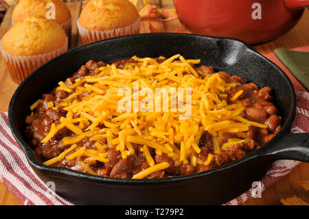 Chili con carne in una padella in ghisa e rabboccato con il formaggio cheddar Foto Stock