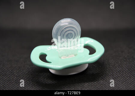 Baby boy succhietto. Colore blu realizzato di silicio il succhietto. Succhietto in silicone su uno sfondo nero. Foto Stock
