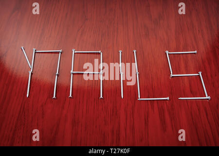 Un gruppo organizzato di chiodi formante la parola chiodi Foto Stock