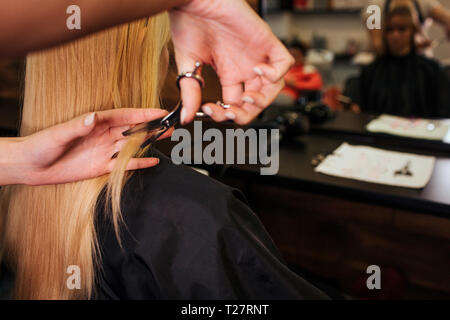 Stretta di mano parrucchieri taglio di capelli biondi. Facendo nuovo taglio di capelli nel salone di bellezza Foto Stock