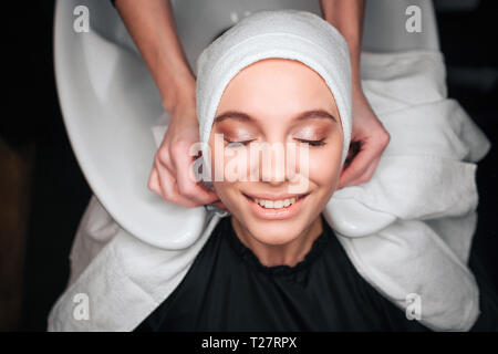 Vista dall'alto di sorridere bella donna soddisfatti dopo lavaggio professionale e trattare i capelli in un salone di bellezza. Efficace cura dei capelli Foto Stock