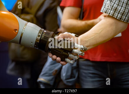 La mano di un uomo stringe la mano con un robot androide. Il concetto di interazione umana con intelligenza artificiale. Foto Stock