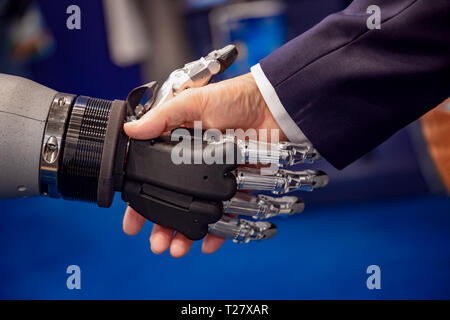 La mano di un uomo d'affari che stringono le mani con un robot androide. Il concetto di interazione umana con intelligenza artificiale. Foto Stock