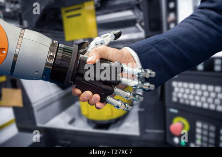 La mano di un uomo d'affari che stringono le mani con un robot androide. Il concetto di interazione umana con intelligenza artificiale. Foto Stock