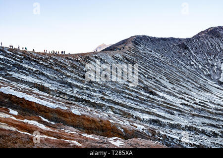 Vista del Kawah Ijen cratere vulcanico con una folla di turisti e miniere di zolfo in corrispondenza del bordo. Java, Indonesia. Foto Stock