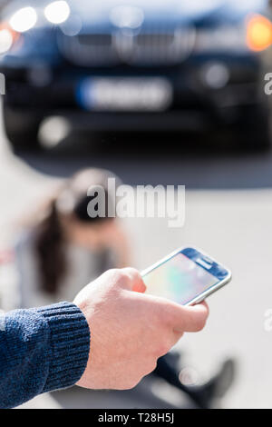 La mano di un uomo di chiamare il numero di emergenza per una donna malata Foto Stock