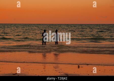 I giovani adulti per divertirsi in spiaggia contro un tramonto dorato Foto Stock