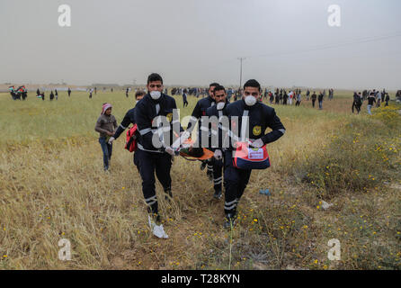 I medici hanno visto che trasporta un manifestante ferito durante gli scontri. I dimostranti palestinesi si sono scontrati con le forze israeliane nella scia di un milione di forte protesta sul terreno, rivendicano il diritto di tornare in patria al confine tra Israele e la striscia di Gaza in Khan Yunis nel sud della striscia di Gaza. Il Ministero della Sanità in Hamas-eseguire detto settore tre palestinesi sono stati uccisi dal fuoco israeliano durante gli scontri. Foto Stock