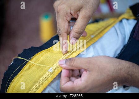 Un sarto preparare il tocco finale di un bisht, un abbigliamento uomo in Qatar Foto Stock