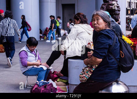 Donna con pedicure in strada trafficata, donna più anziana in primo piano guardando la telecamera, Kowloon, Hong Kong Foto Stock