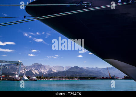Porto di Carrara, Italia. La nave di crociera scoperta nel Dock. Prua di nave si siede diagonalmente attraverso il telaio con le montagne sullo sfondo Foto Stock