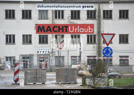 27 marzo 2019, Meclemburgo-Pomerania, Prora: un cartello con la dicitura "ACHT Urlaub' (MACHT holiday) si blocca sulla facciata del centro di documentazione Prora nei locali della KdF località balneare di prora nel comune di Binz sull'isola di Rügen. Prora è sulla strada per diventare un'oasi turistica di benessere sull'isola di Rügen. I nazisti avevano già presente nella mente con il loro gigantesco KdF località balneare. L'organizzazione nazista Kraft durch Freude (kdf) prevista una stazione balneare per 20.000 persone negli anni trenta. Rimase incompiuta, vacanzieri mai arrivati. Con il beginni Foto Stock