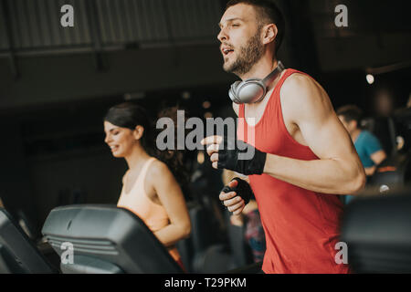 Coppia giovane in esecuzione sul tapis roulant in palestra moderna Foto Stock