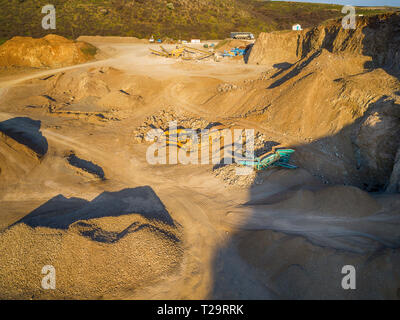 Vista panoramica al tramonto della cava di ghiaia,mining di costruzione gialla ghiaia, ghiaia di pompaggio con l aiuto di potenti pompe, post-apocalittico landscapе Foto Stock