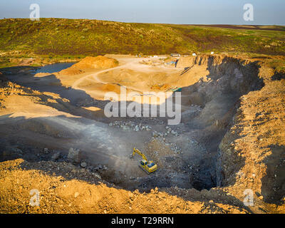 Vista panoramica al tramonto della cava di ghiaia,mining di costruzione gialla ghiaia, ghiaia di pompaggio con l aiuto di potenti pompe, post-apocalittico landscapе Foto Stock