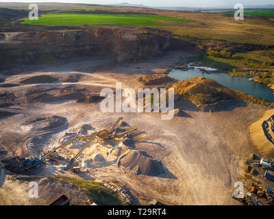 Vista panoramica al tramonto della cava di ghiaia,mining di costruzione gialla ghiaia, ghiaia di pompaggio con l aiuto di potenti pompe, post-apocalittico landscapе Foto Stock