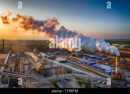 La produzione di tavole di legno, il fumo dai tubi crea inquinamento,Burgas,Bulgaria,al tramonto.di colpo da fuco. Foto Stock