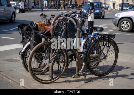 Devizes, Wiltshire, Inghilterra, Regno Unito, marzo 2019. Due turisti biciclette bloccato ad un supporto sicuro sulla piazza del mercato Devizes. Foto Stock