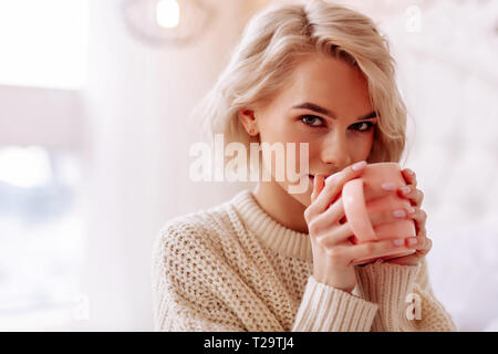 Giovane bella donna con bob cut godendo gustoso tè Foto Stock