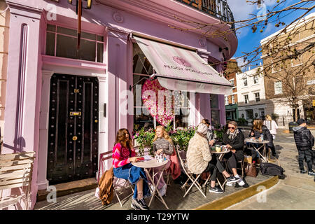 Persone che siedono fuori Peggy Porschen torte, a Belgravia , un negozio di torte noto per il suo impressionante esterno color rosa pastello, Londra, Regno Unito Foto Stock