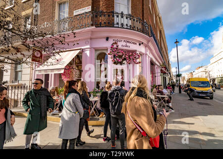 Persone che siedono fuori Peggy Porschen torte, a Belgravia , un negozio di torte noto per il suo impressionante esterno color rosa pastello, Londra, Regno Unito Foto Stock